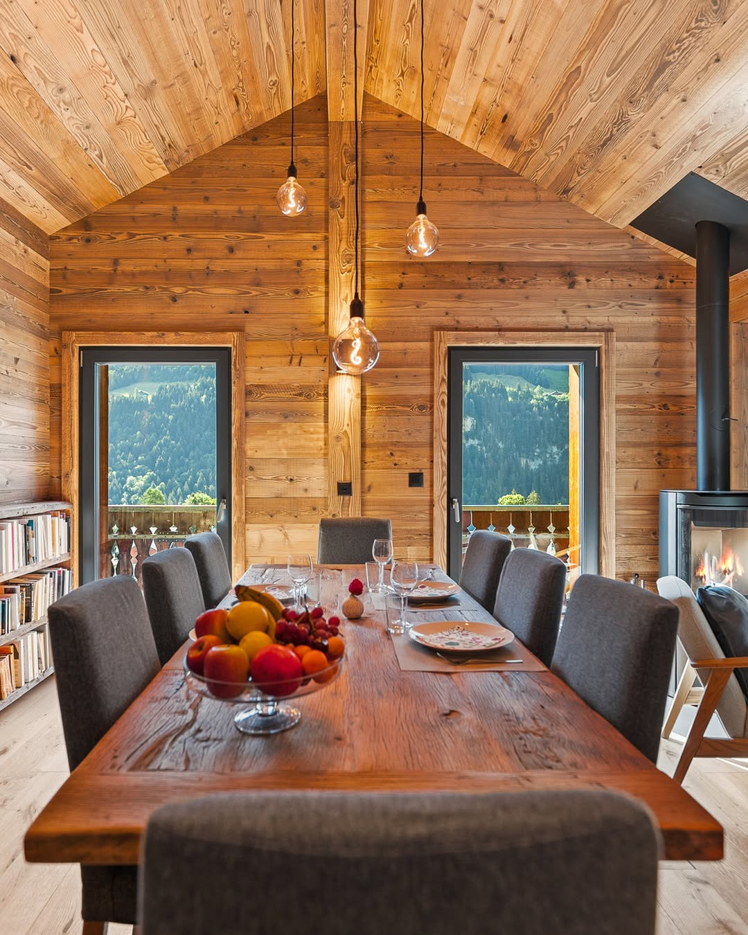 Une table dressée dans un intérieur en bois, face à la montagne